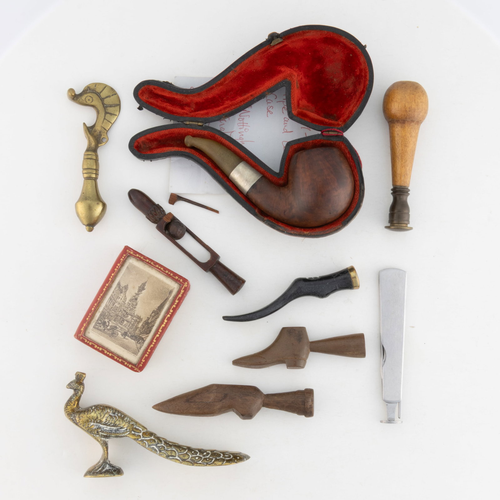 ASSORTED PIPE / SMOKING AND OTHER ACCESSORIES: ASSORTED PIPE / SMOKING AND OTHER ACCESSORIES, including two carved shoe-form tampers; a carved whimsy tamper; and a leather book-form matchbox holder. 20th century. Pipe in case 5 1/4" LOA. Prov