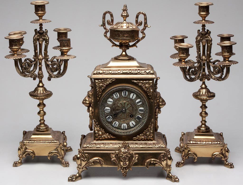 CONTINENTAL BRASS THREE-PIECE CLOCK GARNITURE SET: CONTINENTAL BRASS THREE-PIECE CLOCK GARNITURE SET, comprising a central clock, the movement marked "P.R", and a pair of side candelabra, each raised on four claw feet. With pendulum and key. First qua