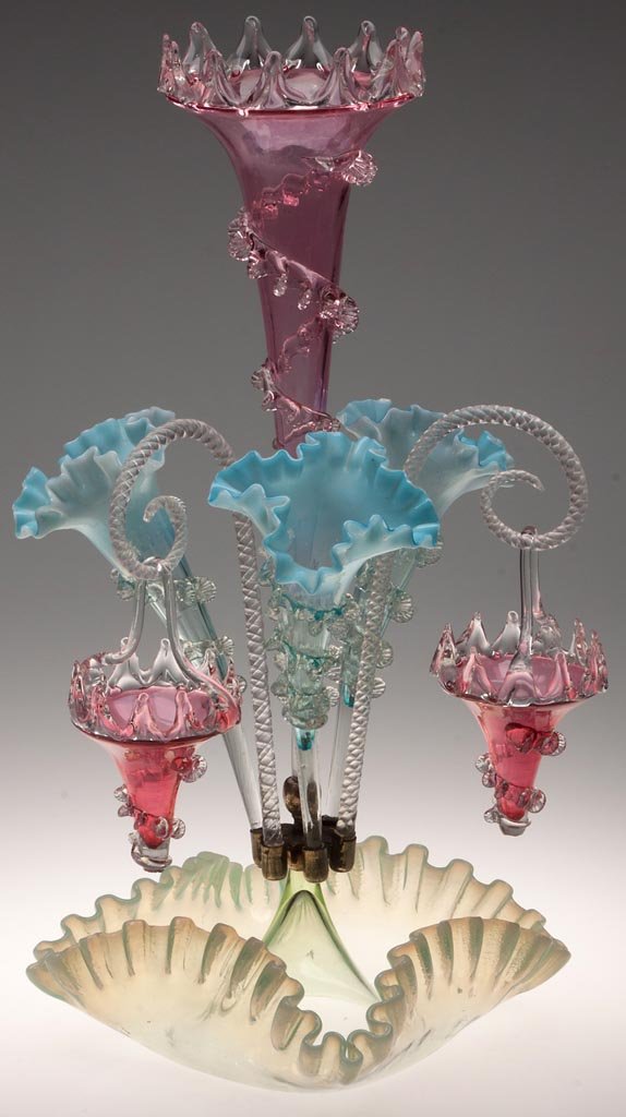 VICTORIAN GLASS EPERGNE: VICTORIAN GLASS EPERGNE, cranberry, blue opalescent, vaseline (uranium) opalescent and colorless, fitted with four vases each having applied colorless rigaree, and two Sheppard's crook arms each hung 