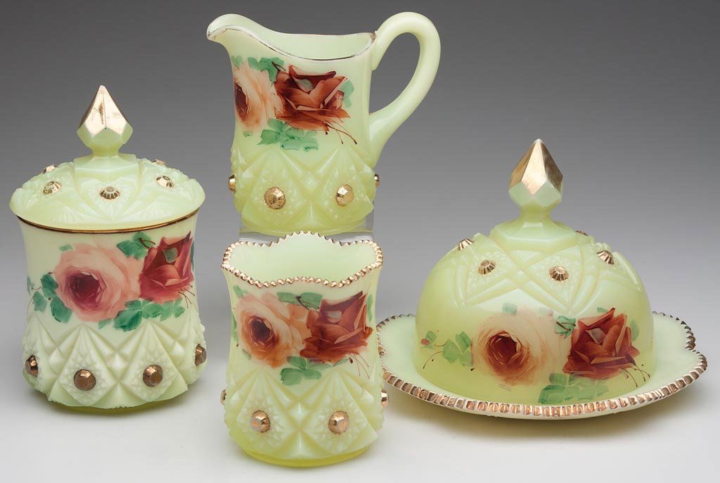DIAMOND WITH PEG FOUR-PIECE TABLE SET: DIAMOND WITH PEG FOUR-PIECE TABLE SET, custard with polychrome rose and gilt decoration, comprising a covered butter dish, covered sugar bowl, creamer and a spooner, three examples marked "Krys-tol" i