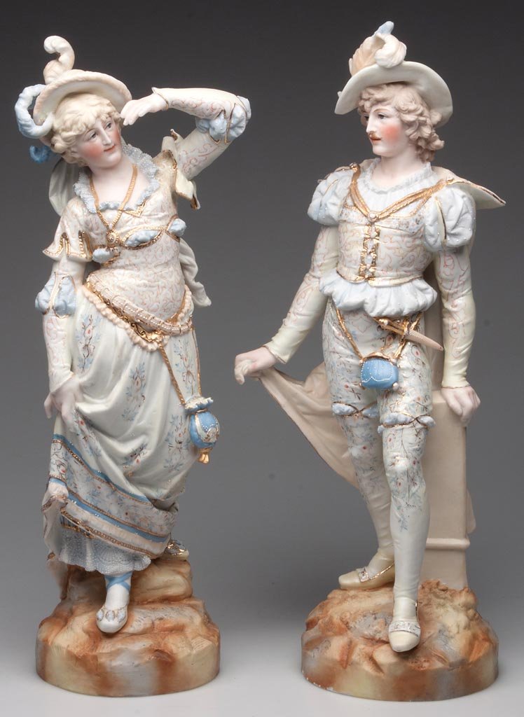 CONTINENTAL BISQUE PORCELAIN PAIR OF LARGE FIGURES: CONTINENTAL BISQUE PORCELAIN PAIR OF LARGE FIGURES, depicting a female and a male outfitted in detailed historical dress of the 15th century with mercury-gilt details, both standing on rocky mounds, e