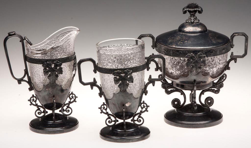 TREE OF LIFE THREE-PIECE TABLE SET: TREE OF LIFE THREE-PIECE TABLE SET, colorless, comprising a covered butter dish, creamer and spooner, each in original quadruple-plate frame, marked "WEBSTER / 3 / MFG Co." Portland Glass Co. Fourth q