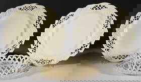 ENGLISH RETICULATED CREAMWARE CERAMIC TABLE ARTICLES, LOT OF FOUR: ENGLISH RETICULATED CREAMWARE CERAMIC TABLE ARTICLES, LOT OF FOUR, comprising two Leeds-style plates with Queen's-shaped rims, having six pierced designs to border and embossed swag and ribbon bet