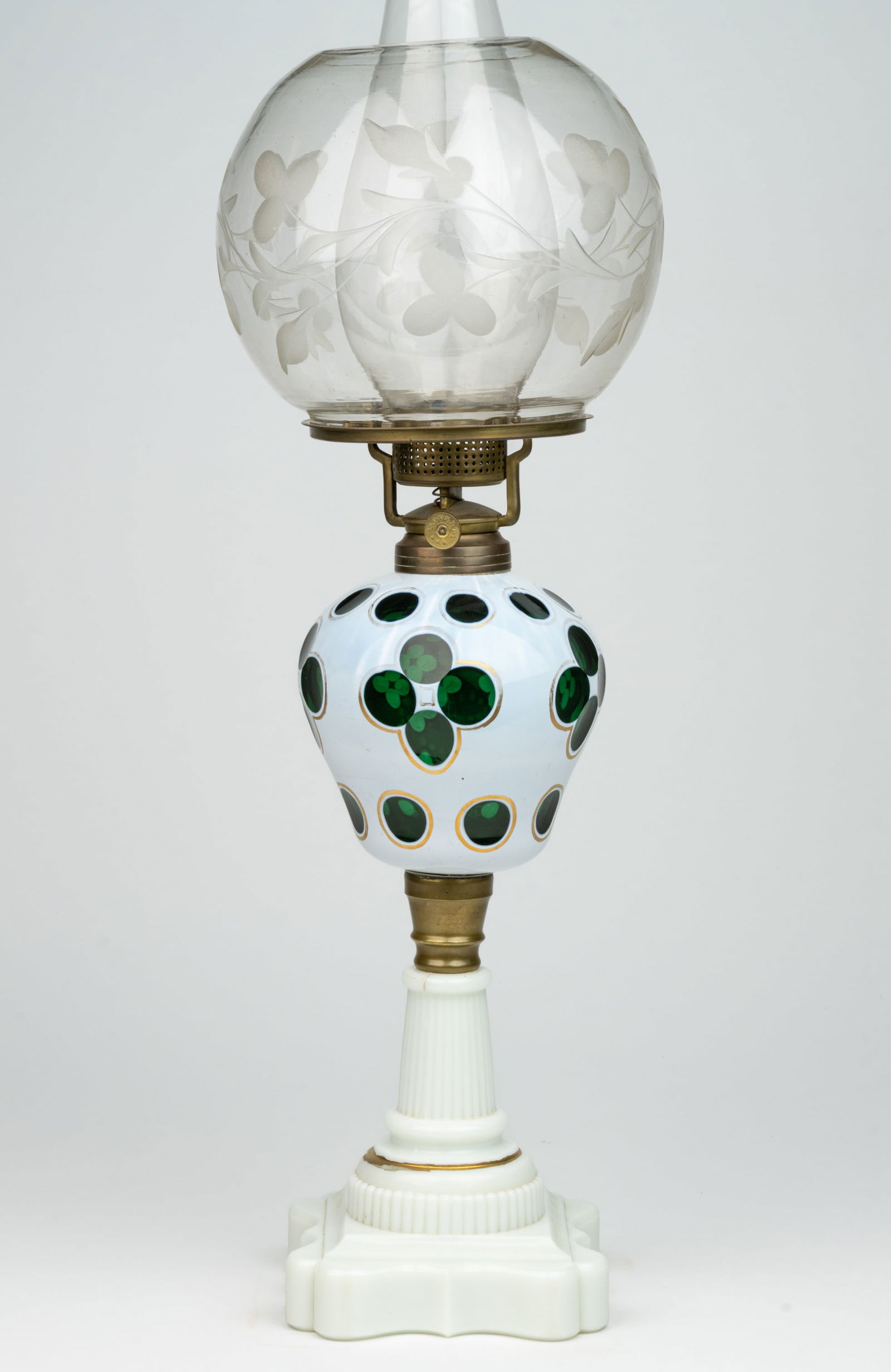 CUT OVERLAY QUATREFOIL KEROSENE STAND LAMP: CUT OVERLAY QUATREFOIL KEROSENE STAND LAMP, opaque white cut to deep emerald green pyriform font, gilt decorated outlining to the cuttings, opaque white Baroque base with gilt decoration, br