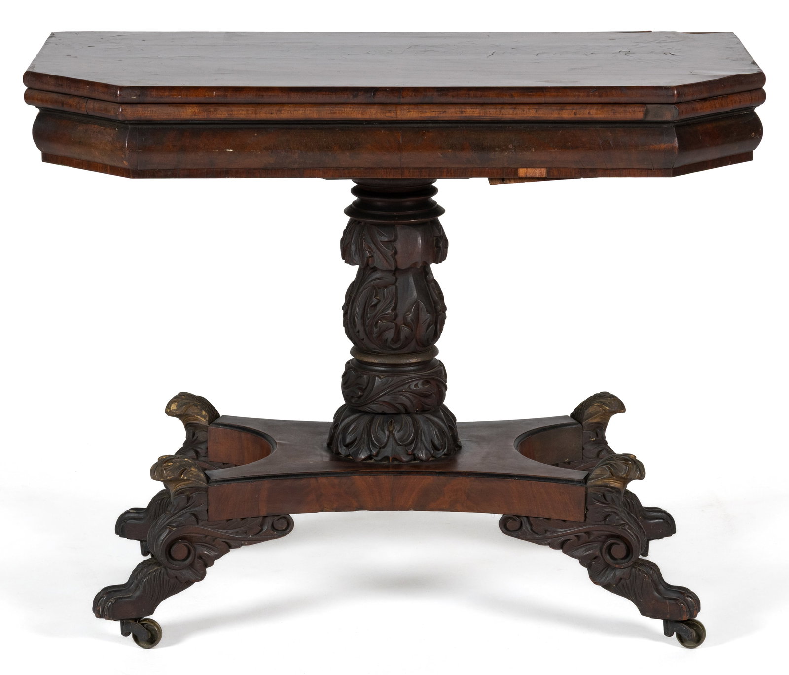 AMERICAN CLASSICAL CARVED MAHOGANY GAMES TABLE: AMERICAN CLASSICAL CARVED MAHOGANY GAMES TABLE, the shaped hinged mahogany-veneered top opens to reveal an elaborately carved surface, and is supported by a molded skirt on a central highly-carved ped