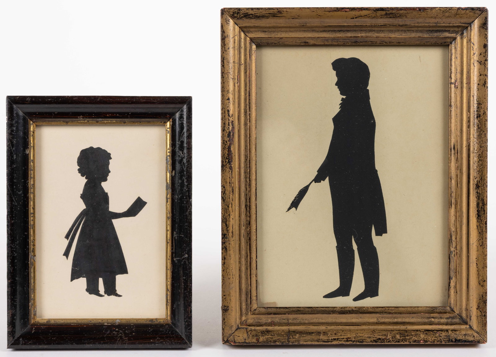 AMERICAN / BRITISH SCHOOL (19TH CENTURY) CUT-AND-PASTED SILHOUETTES, LOT OF TWO: AMERICAN / BRITISH SCHOOL (19TH CENTURY) CUT-AND-PASTED SILHOUETTES, LOT OF TWO, each standing full-figure, one depicting a girl holding a book/letter, the other a young gentleman/student holding a qu