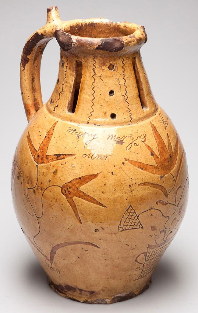 LARGE BRITISH REDWARE DATED PUZZLE JUG: LARGE BRITISH REDWARE DATED PUZZLE JUG, the slip-decorated sgraffito jug of baluster form, the strap handle with nozzle to top, the collar with space for four nozzles, with ocher-yellow glaze, incised