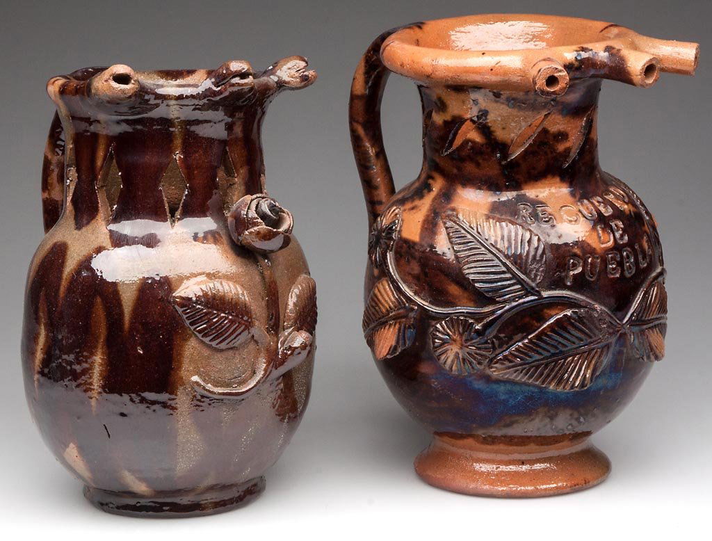 PUEBLA (MEXICO) EARTHENWARE PUZZLE JUGS, LOT OF TWO: PUEBLA (MEXICO) EARTHENWARE PUZZLE JUGS, LOT OF TWO, both of red earthenware baluster form, the first with three snakes' heads forming the nozzles on the collar, over a diamond-reticulated neck, the b