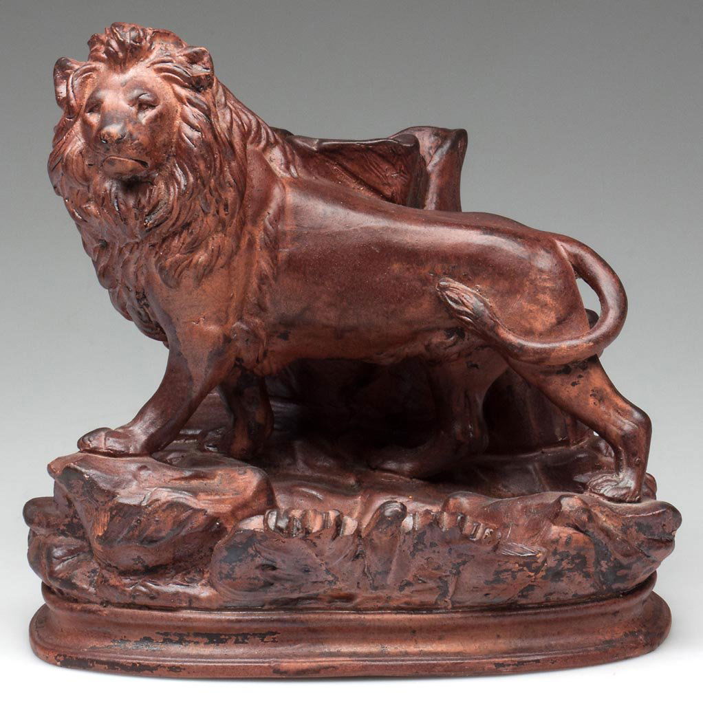 GERMAN POTTERY FIGURE OF A STANDING LION: GERMAN POTTERY FIGURE OF A STANDING LION, by P. LIEMANN & CO., the varnished earthenware figural group standing in front of a spill vase, the rocky-mounded base atop a waisted ovular plinth, impressed