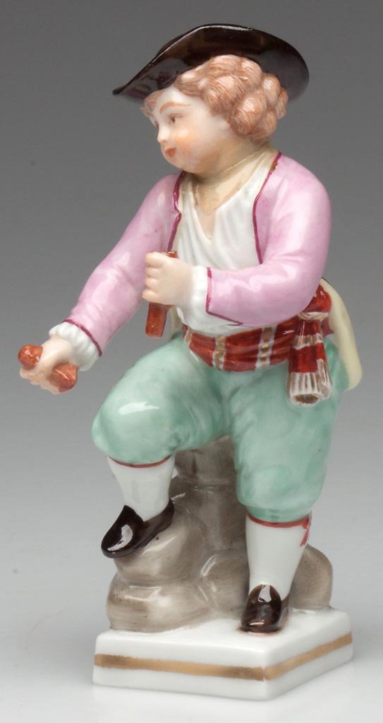 "VIENNA" PORCELAIN FIGURE OF A BOY: "VIENNA" PORCELAIN FIGURE OF A BOY, standing playing with sticks, with his right foot on a mound of rocks, dressed in black hat with red ribbon; pink coat; white shirt; red white and gold belt over pa