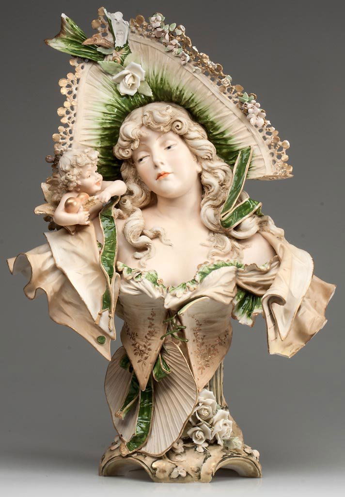 AUSTRIAN (TURN) TEPLITZ AMPHORA PORCELAIN ART NOUVEAU B: AUSTRIAN (TURN) TEPLITZ AMPHORA PORCELAIN ART NOUVEAU BISCUIT PORCELAIN BUST OF A STYLISH WOMAN, BY STELLMACHER, her realistically painted face with eyes cast down, slightly reddened lips and reddish