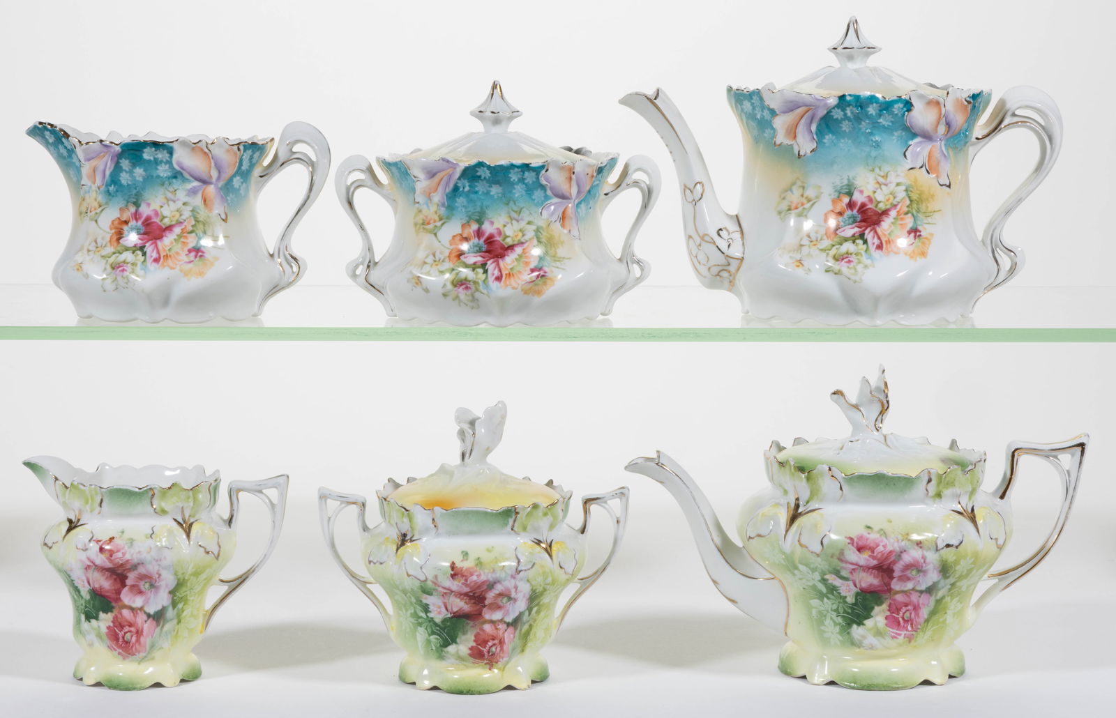 R.S. PRUSSIA PORCELAIN FLORAL MOTIF THREE-PIECE TEA SETS, LOT OF TWO: R.S. PRUSSIA PORCELAIN FLORAL MOTIF THREE-PIECE TEA SETS, LOT OF TWO, comprising one RS Steeple Mold 6 set featuring bright polychrome flowers with teal border and one RSP Mold 25 set having pink