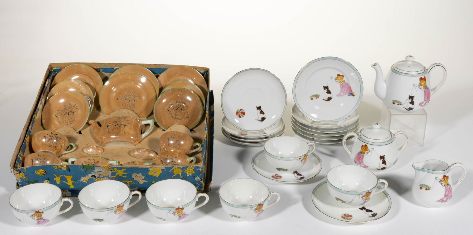 JAPANESE PORCELAIN CAT MOTIF CHILDREN'S TEA SETS, LOT OF TWO: JAPANESE PORCELAIN CAT MOTIF CHILDREN'S TEA SETS, LOT OF TWO, comprising a Nippon 21-piece set featuring black transfer polychrome-decorated scene depicting a girl pulling a turtle with wheel