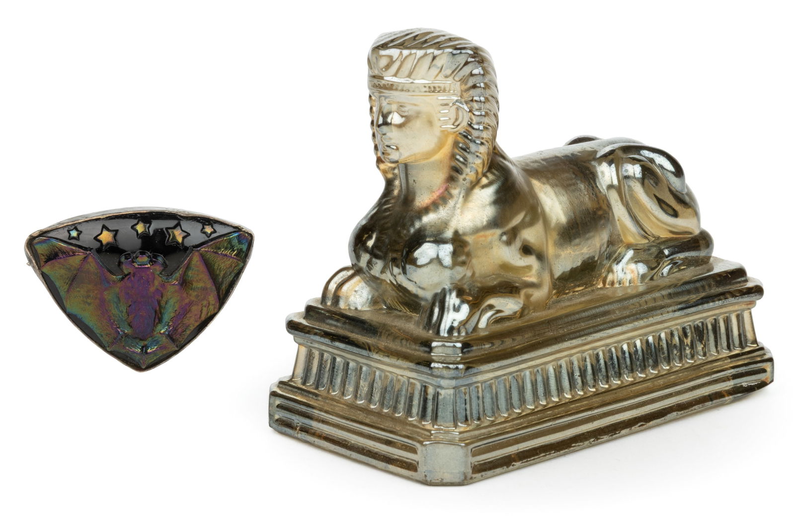 CARNIVAL GLASS NOVELTIES, LOT OF TWO: CARNIVAL GLASS NOVELTIES, LOT OF TWO, comprising an amethyst Flying Bat hatpin set into a silver (unknown fineness) frame with a pin to make a brooch, and a smoke Sphinx figure with an open base. Firs