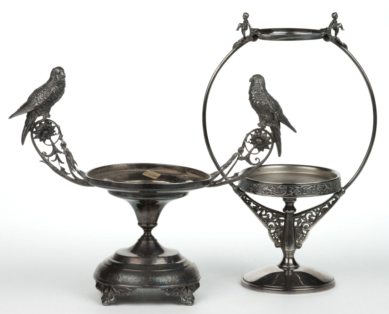 VICTORIAN QUADRUPLE-PLATE BRIDE'S BASKET STANDS, LOT OF TWO: VICTORIAN QUADRUPLE-PLATE BRIDE'S BASKET STANDS, LOT OF TWO, comprising an example with a parakeet perched on each handle, marked for E. G. Webster & Bro. and "86"; and a two-tier ex