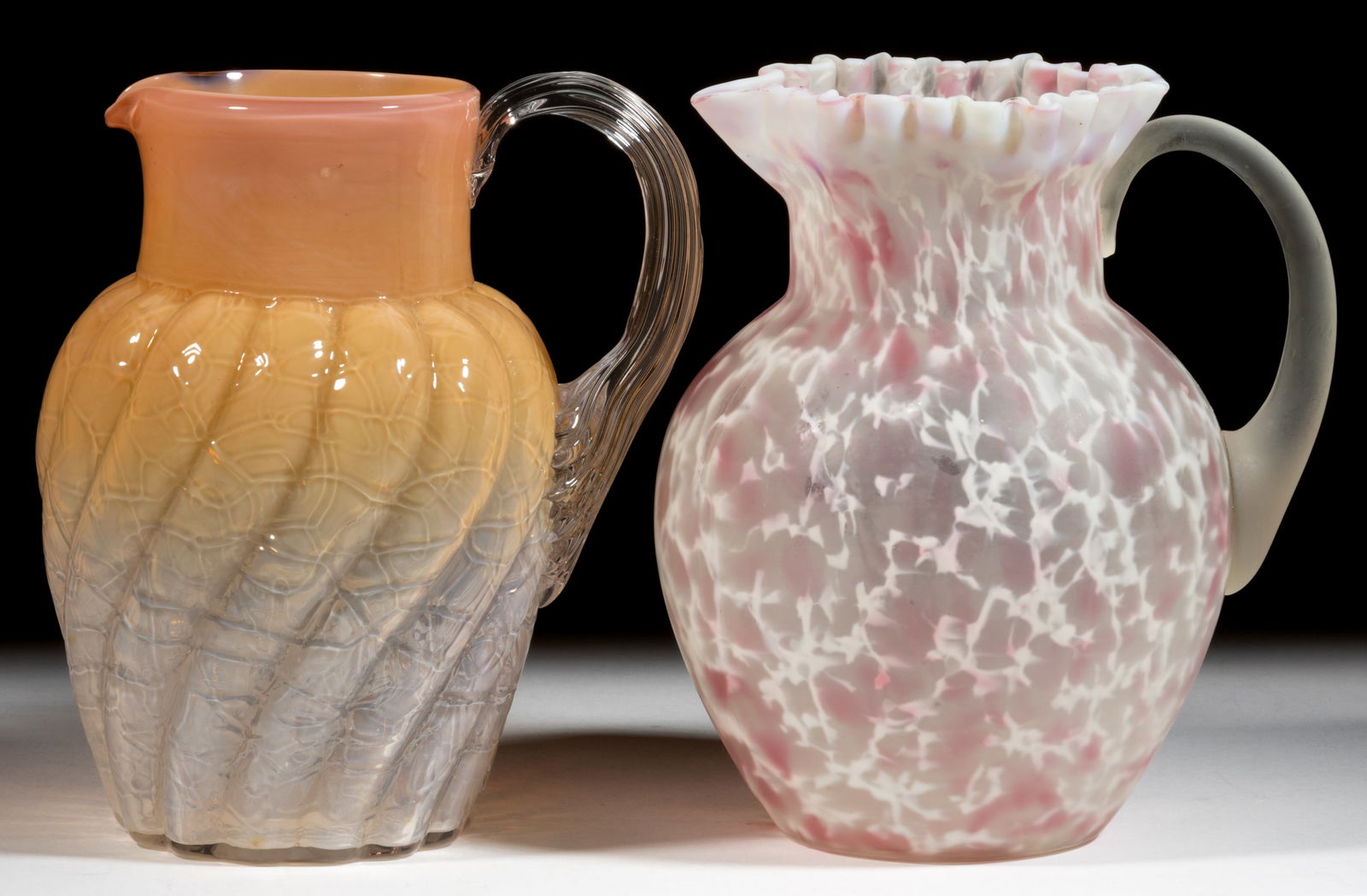ASSORTED VICTORIAN GLASS WATER PITCHERS, LOT OF TWO: ASSORTED VICTORIAN GLASS WATER PITCHERS, LOT OF TWO, comprising a frosted colorless with opal and cranberry spatter example with hexagonal rim and an embossed veined example with Swirl patte