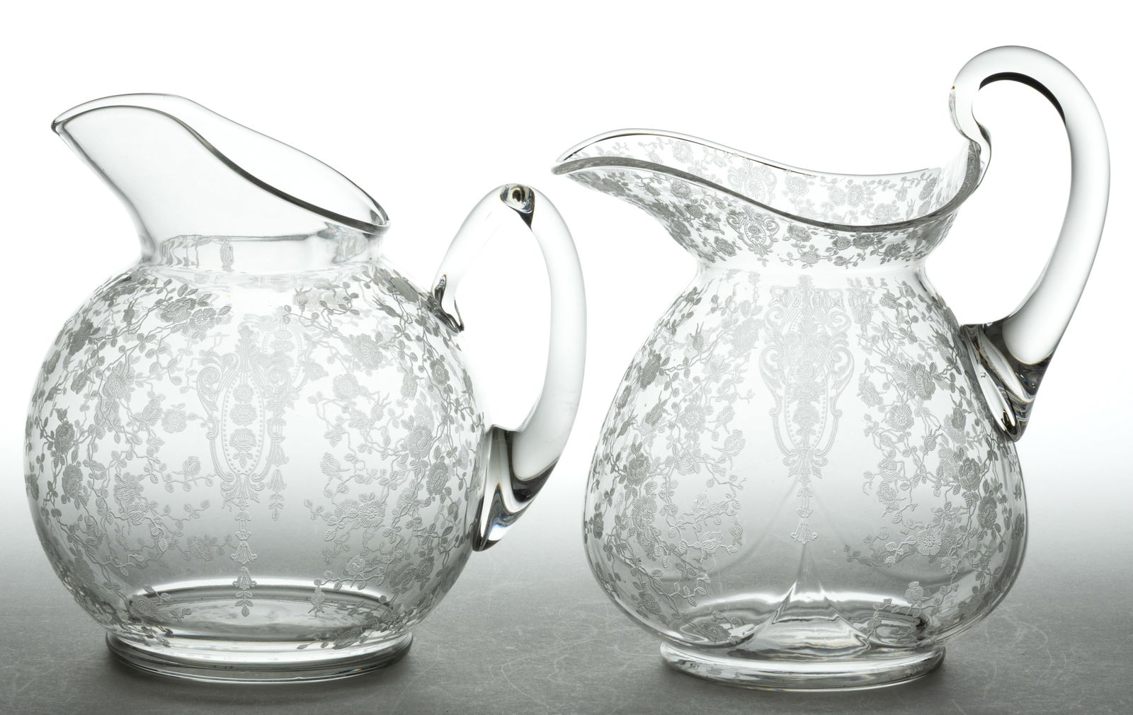 CAMBRIDGE ROSE POINT WATER PITCHERS, LOT OF TWO: CAMBRIDGE ROSE POINT WATER PITCHERS, LOT OF TWO, colorless, comprising a Doulton shape with a high handle and a ball-rom with ice lip. Cambridge Glass Co. Introduced in 1935. 9 1/2" and 8 1/