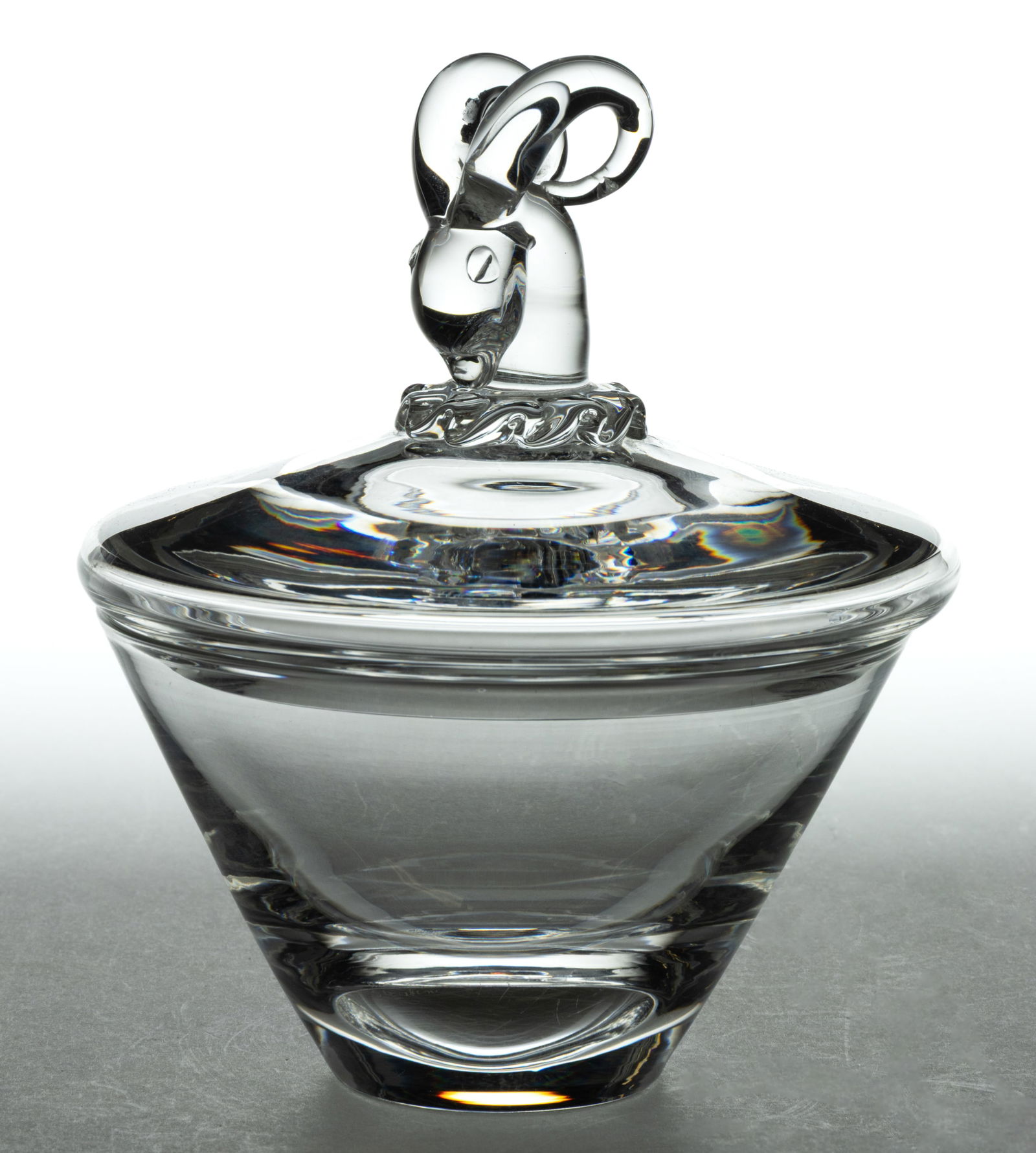 STEUBEN CRYSTAL MID-CENTURY MODERN COVERED CANDY DISH: STEUBEN CRYSTAL MID-CENTURY MODERN COVERED CANDY DISH, colorless lead glass, the conical bowl fitted with a cover featuring an applied hand-formed ram's/gazelle's head finial, signed in script