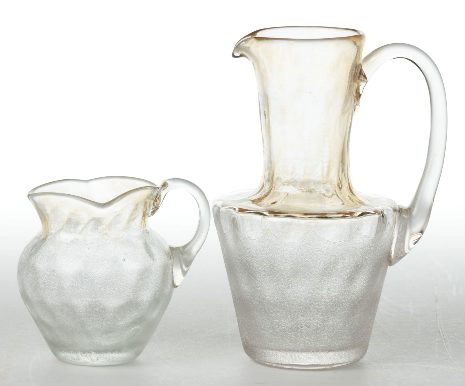 POMONA - FIRST-PATENT ETCHING ART GLASS DIMINUTIVE / MINIATURE PITCHERS, LOT OF TWO: POMONA - FIRST-PATENT ETCHING ART GLASS DIMINUTIVE / MINIATURE PITCHERS, LOT OF TWO, each colorless with amber iridescence and Dot-Optic molding, comprising an ovoid miniature pitcher with a square ri