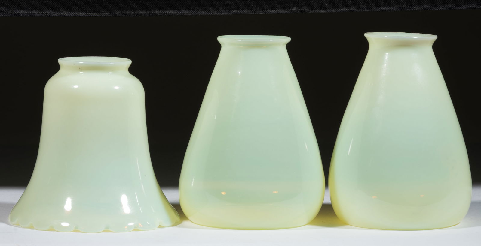ASSORTED VASELINE OPALESCENT ELECTRIC LAMP SHADES, LOT OF THREE: ASSORTED VASELINE OPALESCENT ELECTRIC LAMP SHADES, LOT OF THREE, Vaseline opalescent (reacts under blacklight), comprising a pair in a rounded conical form, and a bell-form example with a tooled rim.