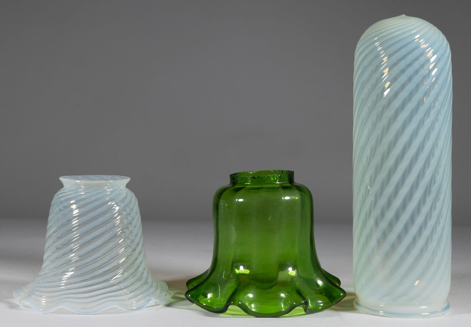 ASSORTED ART GLASS ELECTRIC LAMP SHADES, LOT OF THREE: ASSORTED ART GLASS ELECTRIC LAMP SHADES, LOT OF THREE, comprising two colorless opalescent swirl patterned examples, including a bell-form example with a scalloped top, and a cylinder-form&n