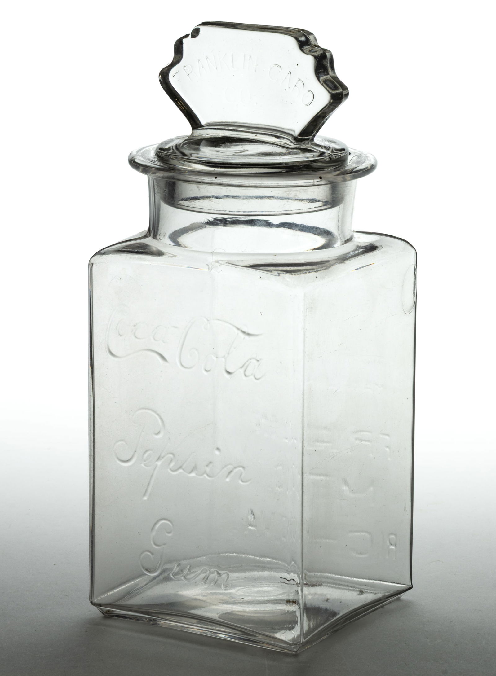COCA-COLA PEPSIN GUM GLASS STORE JAR: COCA-COLA PEPSIN GUM GLASS STORE JAR, colorless, square form with embossed script name to the front and Franklin Mfg. Co. info to back, cover embossed "Franklin Caro Co." Circa 1910. 11 1/4&