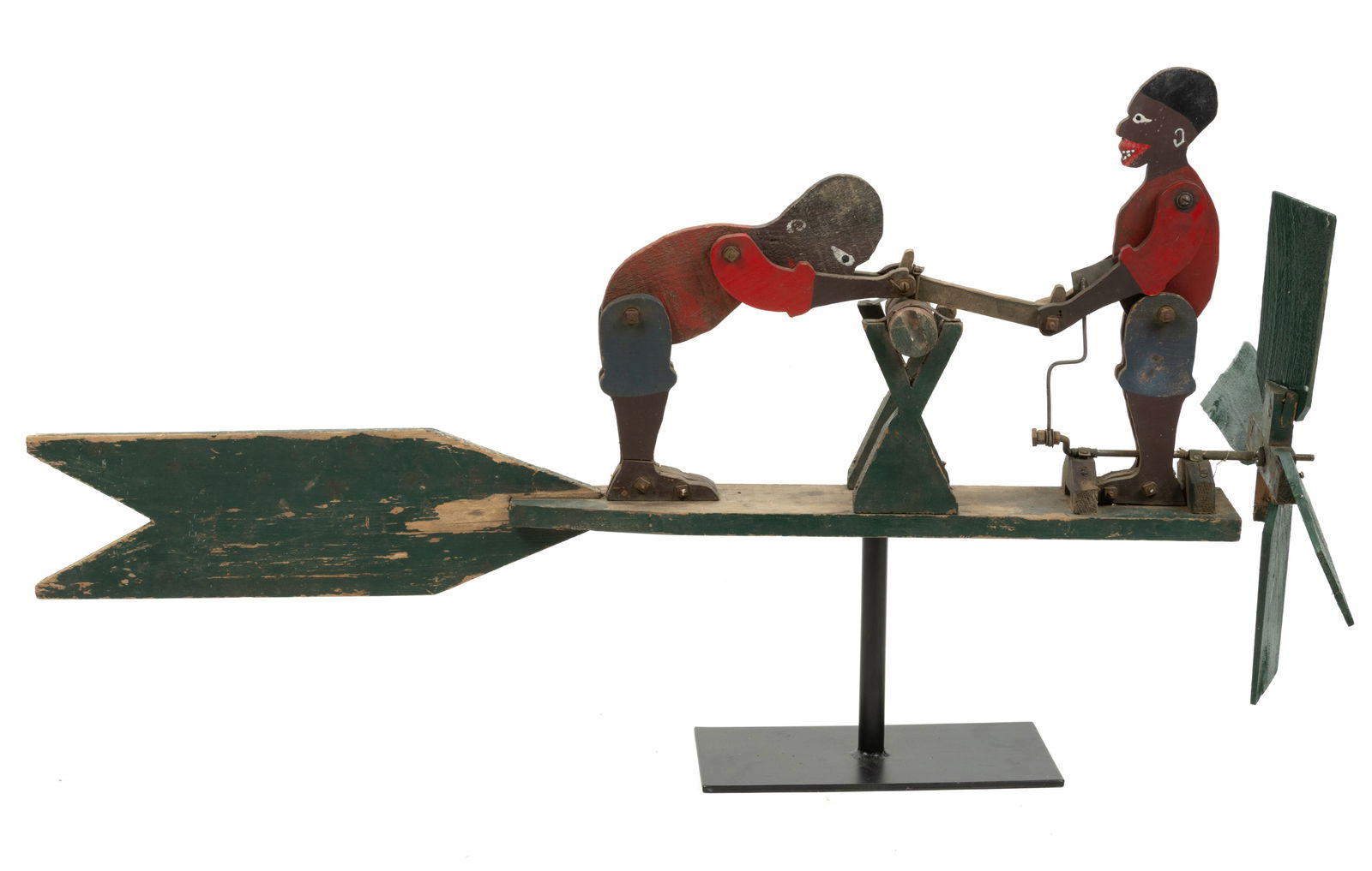 AMERICAN FOLK ART CARVED AND PAINTED WOODEN WHIRLIGIG: AMERICAN FOLK ART CARVED AND PAINTED WOODEN WHIRLIGIG, featuring two stylized African-American figures at a sawhorse, retaining likely original polychrome surface. Presented on a custom iron stand. Ci