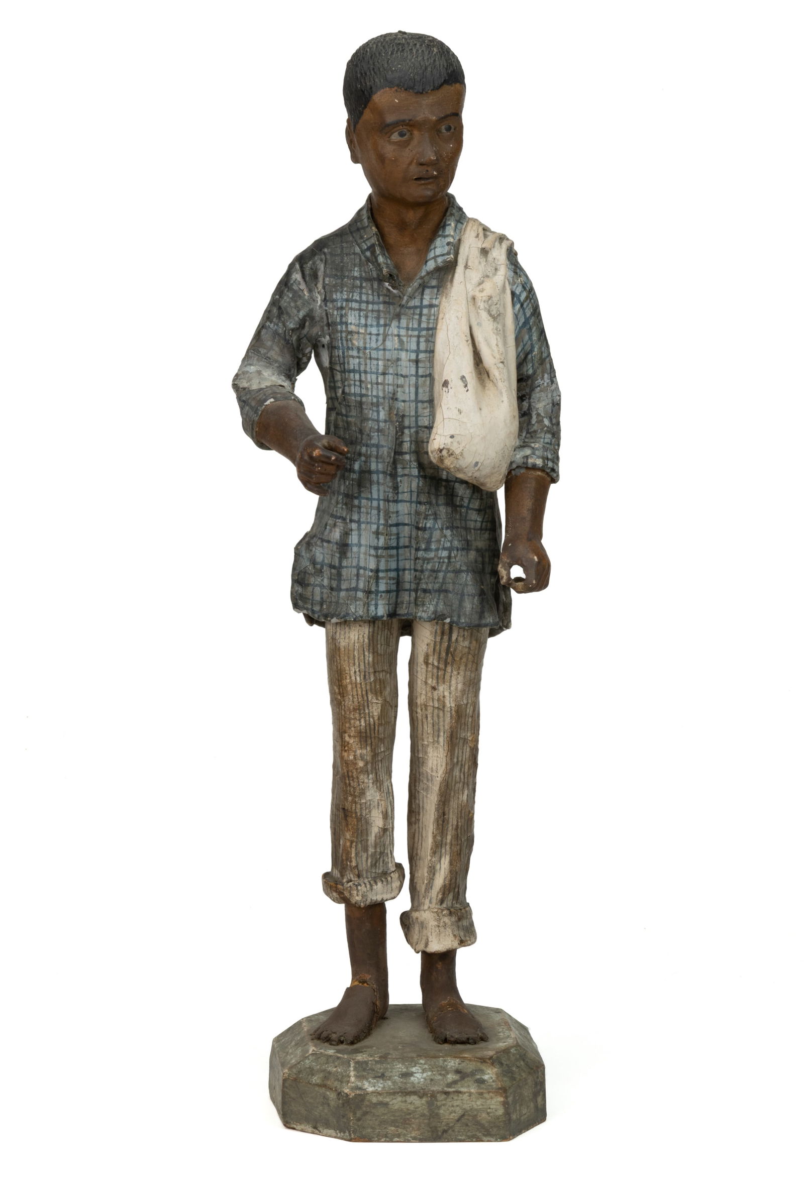 POSSIBLY CENTRAL / SOUTH AMERICAN PAPIER MACHE STATUE / FIGURE OF A MAN: POSSIBLY CENTRAL / SOUTH AMERICAN PAPIER MACHE STATUE / FIGURE OF A MAN, depicting a man with brown-toned skin and short black hair carrying a sack over his shoulder and wearing a plaid shirt with str