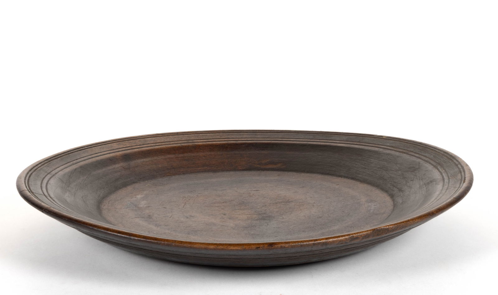 AMERICAN TURNED TREEN CHARGER / DISH: AMERICAN TURNED TREEN CHARGER / DISH, probably maple, low circular form, featuring finely-turned banding to the top edge of the dish with more turned lines to the underside. Retains an early, possibly