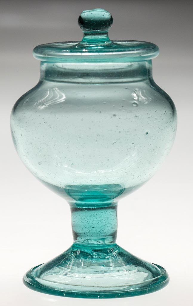 FREE-BLOWN FOOTED SUGAR BOWL AND COVER: FREE-BLOWN FOOTED SUGAR BOWL AND COVER, strong aquamarine, urn-form bowl raised on a drawn solid stem and applied funnel foot with folded rim and rough pontil mark, flat-top cover with pinched flange 