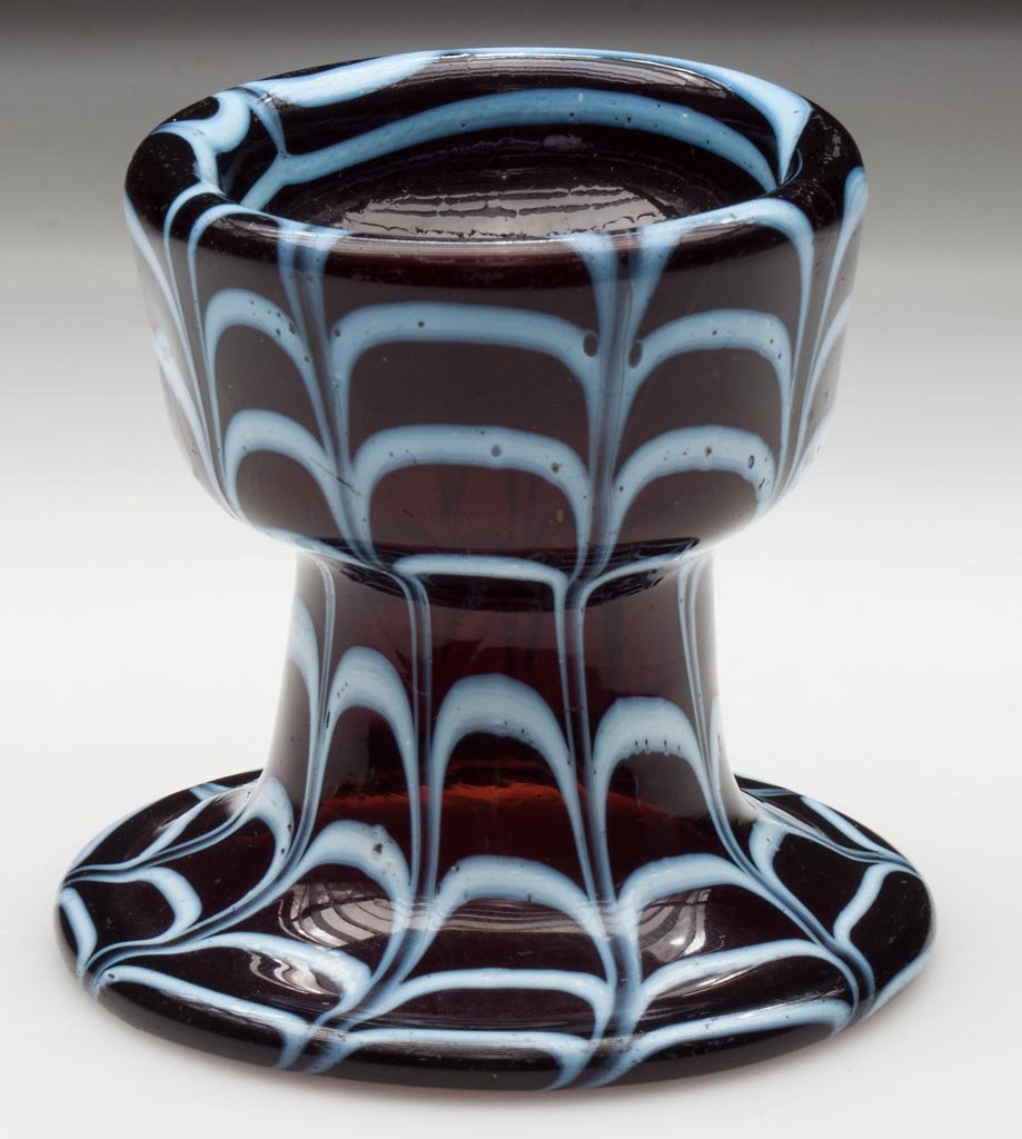 FREE-BLOWN AND DECORATED PEDESTAL SALT: FREE-BLOWN AND DECORATED PEDESTAL SALT, deep amber with opal loopings, raised on a drawn funnel base with folded rim, rough pontil mark in base of bowl. First half 19th century. 3" H, 2 1/2" D rim, 3 