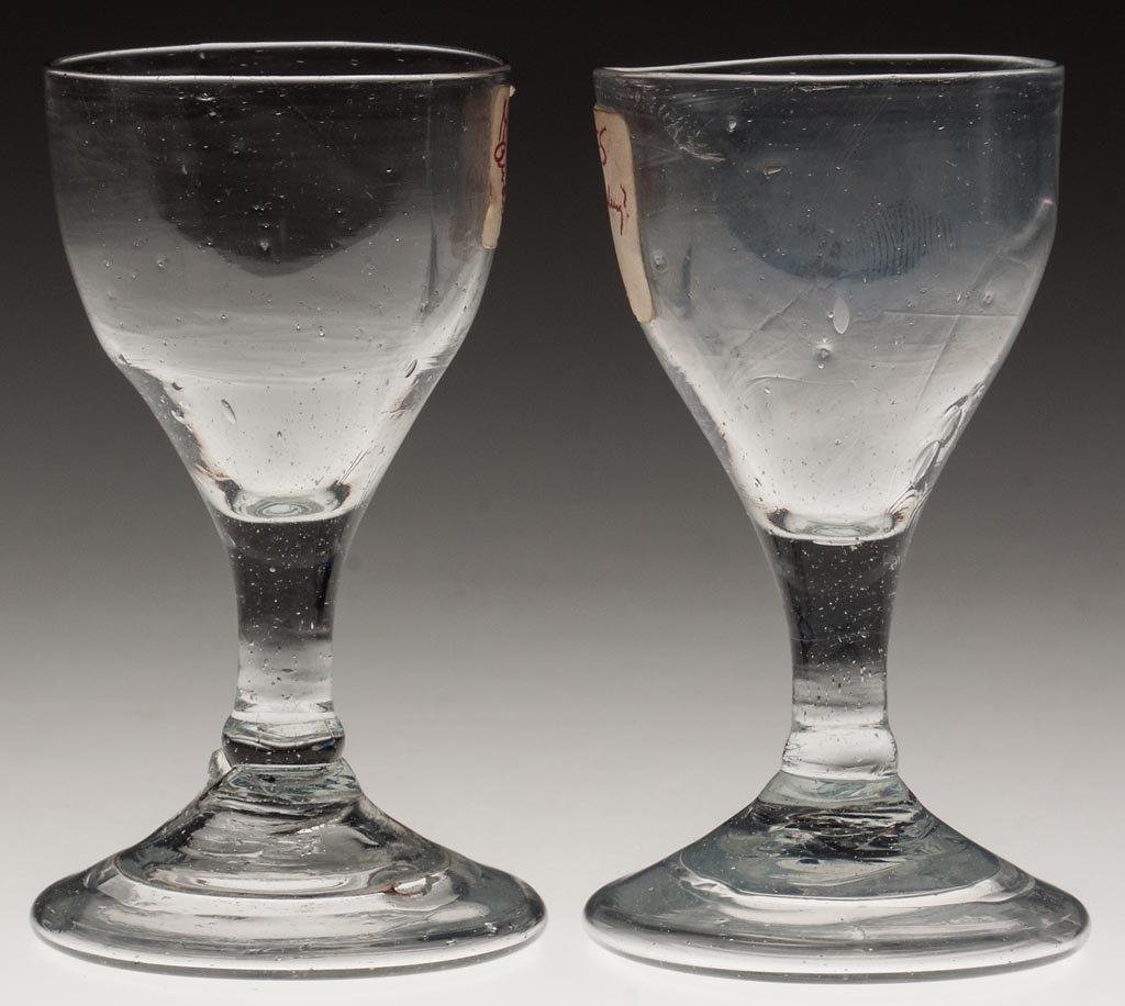 PAIR OF FREE-BLOWN WINE GLASSES,: PAIR OF FREE-BLOWN WINE GLASSES,, colorless lead glass with gray tint, each ogee bowl raised on a drawn stem with slight knop at base, and an applied conical foot with wide folded rim and rough pontil