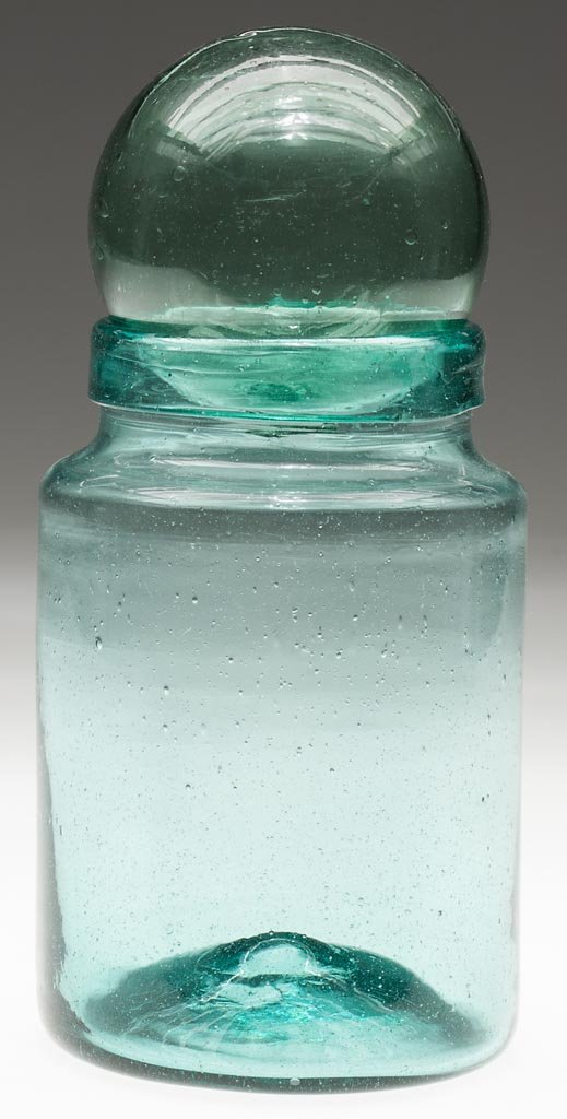 FREE-BLOWN STORAGE JAR: FREE-BLOWN STORAGE JAR, blue-green bottle glass, cylindrical form with sharp shoulder, folded mouth and rough pontil mark. Fitted with a light green ball cover with rough pontil mark. Possibly Midwest
