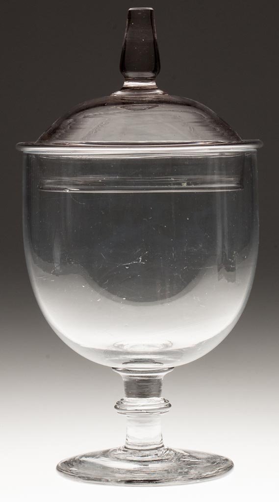 FREE-BLOWN JAR AND COVER: FREE-BLOWN JAR AND COVER, colorless lead glass, deep, cup-shape bowl raised on an applied solid stem with annular knop and a thick, circular foot with rough pontil mark; the domed cover with a folded 