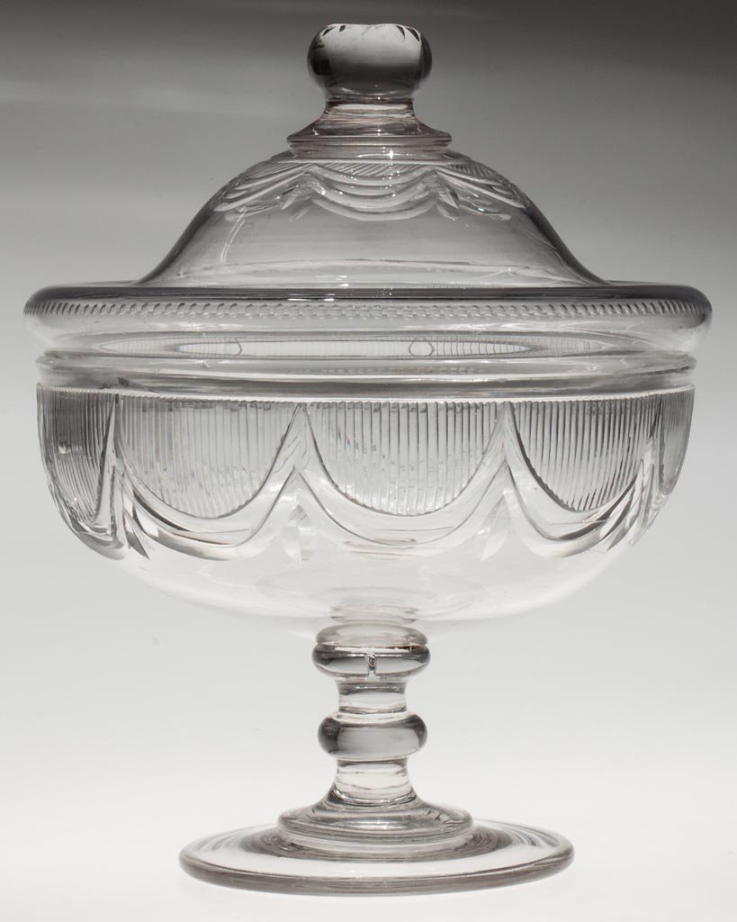 FREE-BLOWN AND CUT FESTOON FOOTED PUNCH BOWL AND COVER: FREE-BLOWN AND CUT FESTOON FOOTED PUNCH BOWL AND COVER, colorless lead glass, deep bowl raised on a medial-knop stem and thick foot with polished pontil mark, domed cover with pattern below the applie