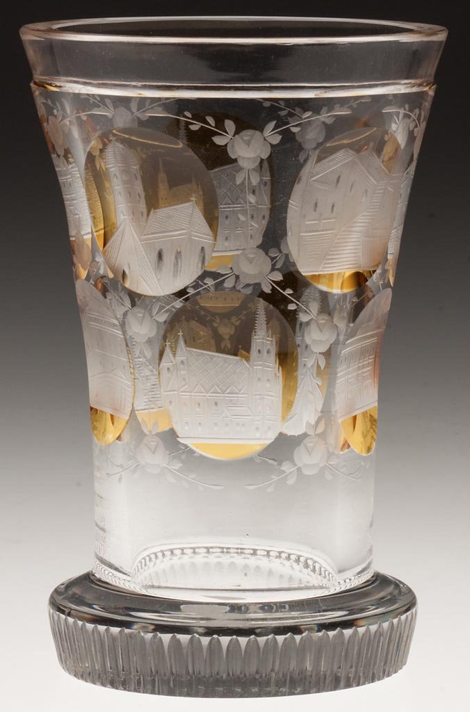 BOHEMIAN ENGRAVED SOUVENIR TUMBLER: BOHEMIAN ENGRAVED SOUVENIR TUMBLER, colorless with nine amber-stained reserves, each engraved with a different building, floral engraving between reserves, signed "Wien" under base. Probably a souveni