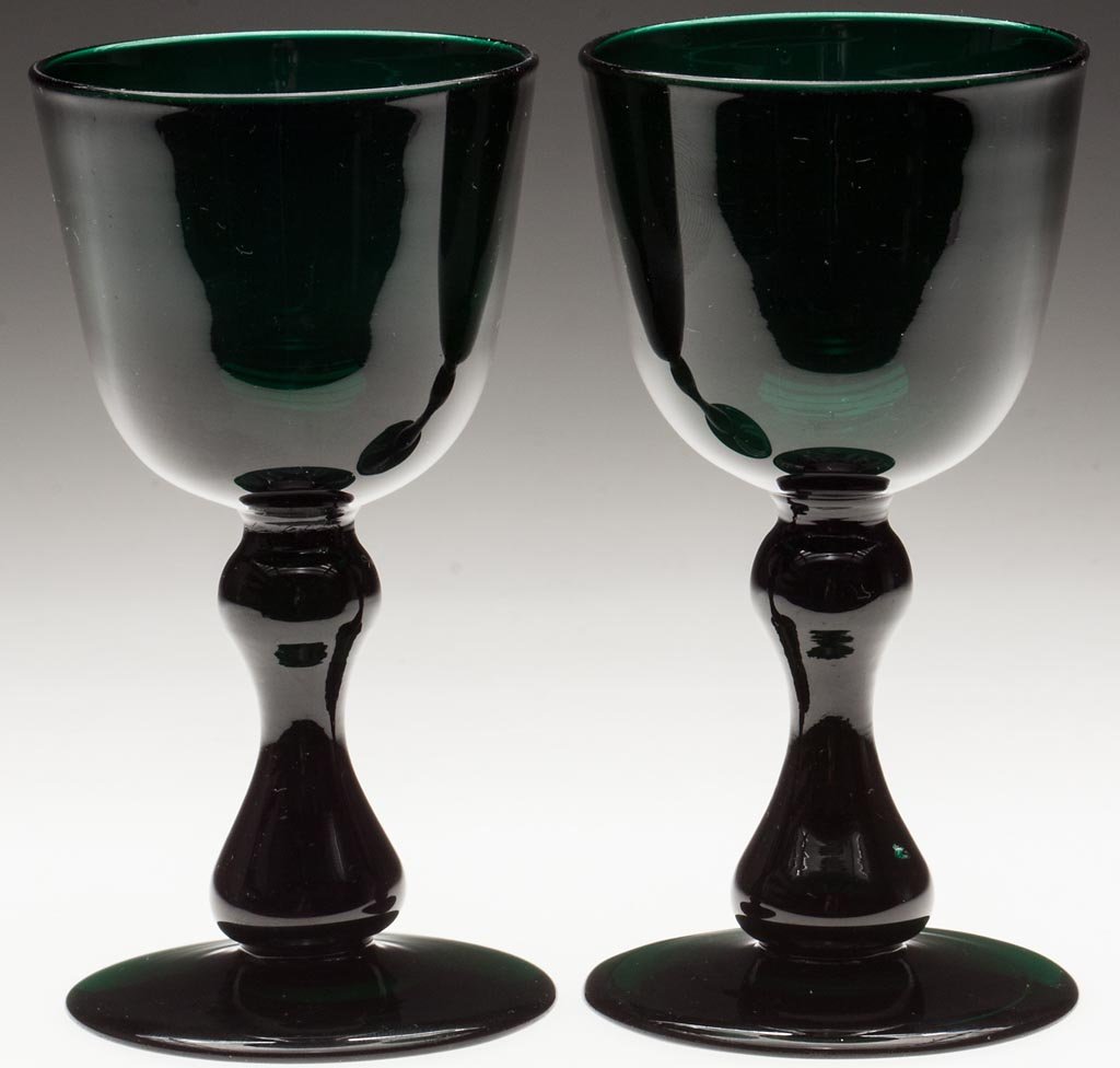 PAIR OF FREE-BLOWN CLARET GLASSES: PAIR OF FREE-BLOWN CLARET GLASSES, deep emerald green lead glass, each rounded-bottom bowl raised on a hollow hour-glass stem and circular foot with polished pontil mark. Second half 19th century. 5 1