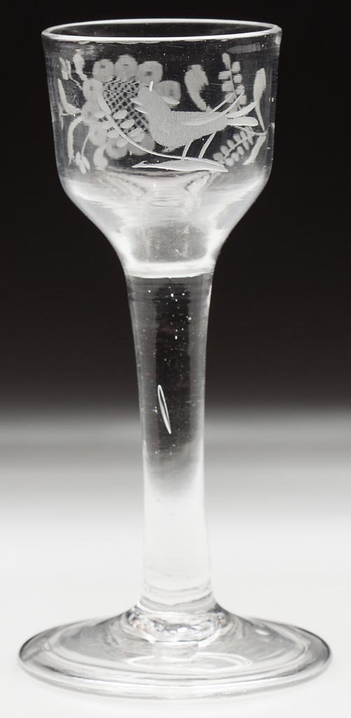 FREE-BLOWN AND ENGRAVED WINE GLASS: FREE-BLOWN AND ENGRAVED WINE GLASS, colorless, ogee bowl engraved with a bird on branch backed with a floral spray, raised on a tall solid stem and conical foot with folded rim and rough pontil mark. 