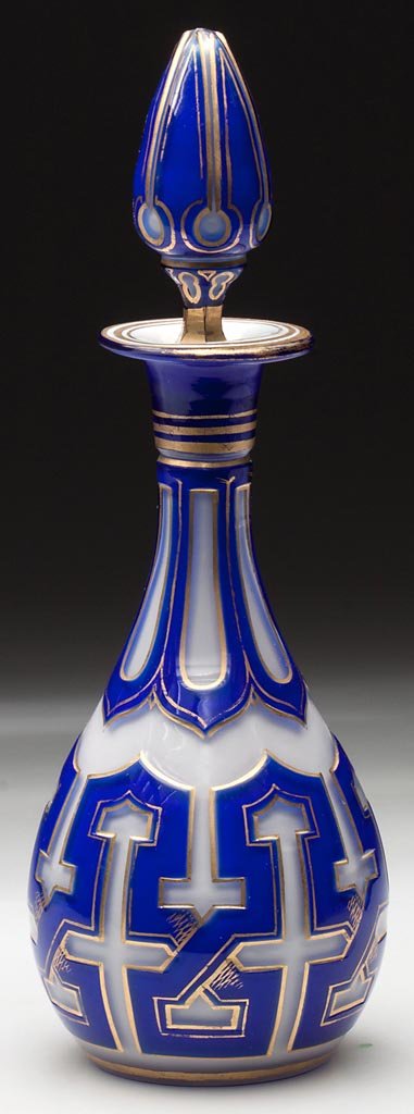 CUT DOUBLE OVERLAY COLOGNE BOTTLE: CUT DOUBLE OVERLAY COLOGNE BOTTLE, blue to opal-cased colorless with gilt decoration, elongated pyriform with flanged mouth and polished pontil mark, original air-trap stopper. Maude B. Feld sticker u