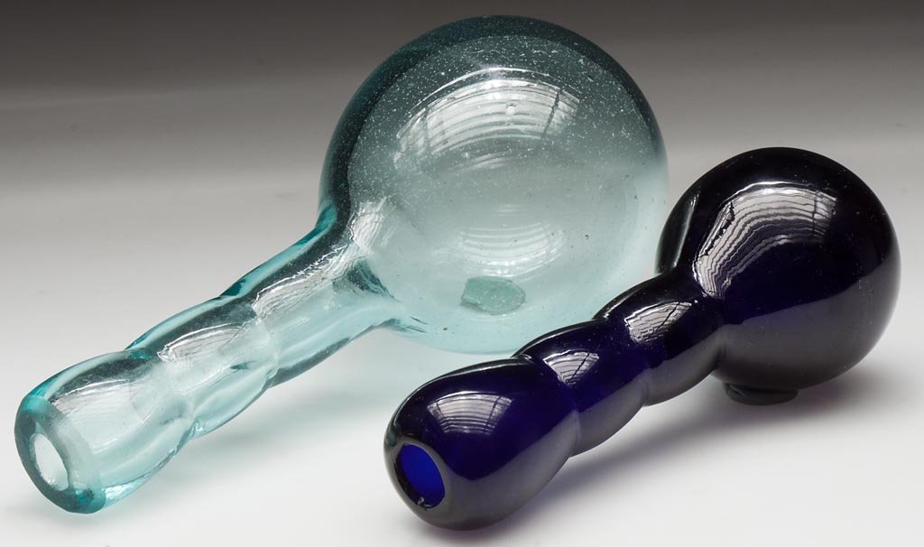 FREE-BLOWN DARNING BALLS, LOT OF TWO: FREE-BLOWN DARNING BALLS, LOT OF TWO, cobalt blue and aquamarine, one handle with ground, open-pontil end and the other with a polished end. 19th century. 5" and 6 1/2" L.