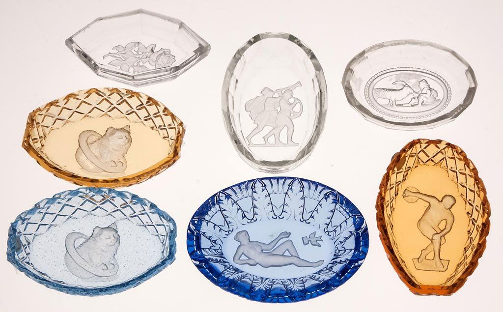 INTAGLIO GLASS OPEN SALTS, LOT OF SEVEN: INTAGLIO GLASS OPEN SALTS, LOT OF SEVEN, amber, blue and colorless, ovoid form with various patterns including two cats, goat, nude lady, man with bowling ball and a rose sprig. First half 20th centur