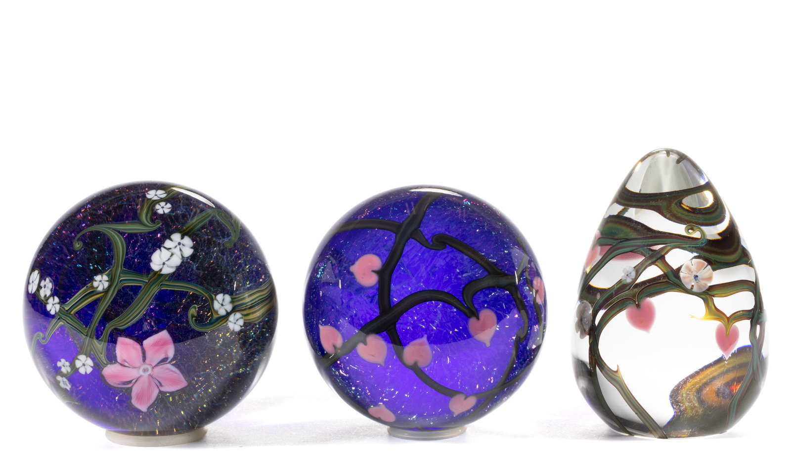 ZELLIQUE STUDIOS FLOWER AND VINE ART GLASS PAPERWEIGHTS, LOT OF THREE: ZELLIQUE STUDIOS FLOWER AND VINE ART GLASS PAPERWEIGHTS, LOT OF THREE, comprising two examples having pink heart-form flowers connected by variegated green stems, one being egg form and the other trad