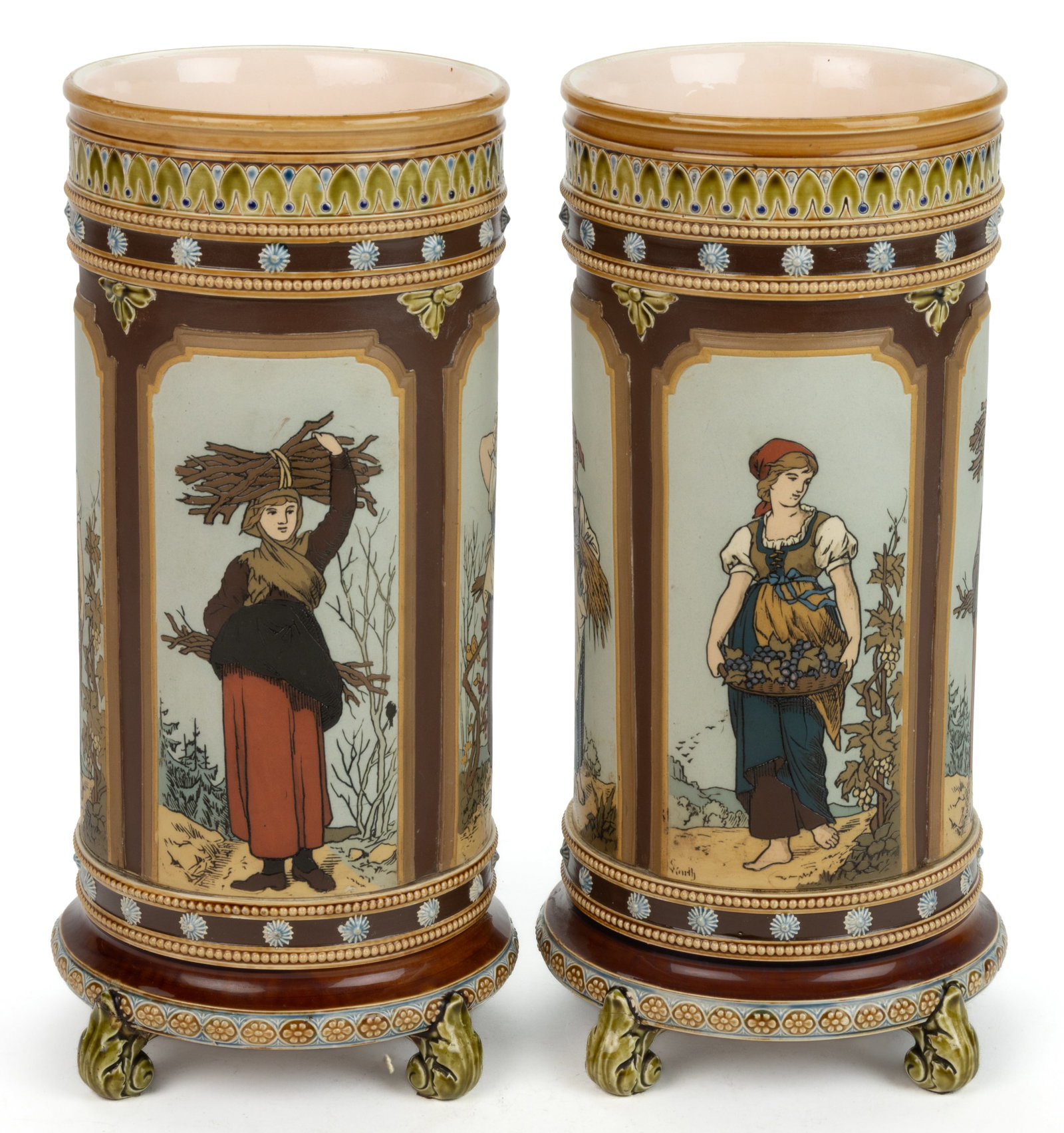GERMAN METTLACH WOMAN MOTIF CERAMIC VASE PAIR: GERMAN METTLACH WOMAN MOTIF CERAMIC VASE PAIR, mold number 1462, each of cylindrical form and resting on four acanthus leaf feet, featuring etched design with polychrome hand-painted decoration having