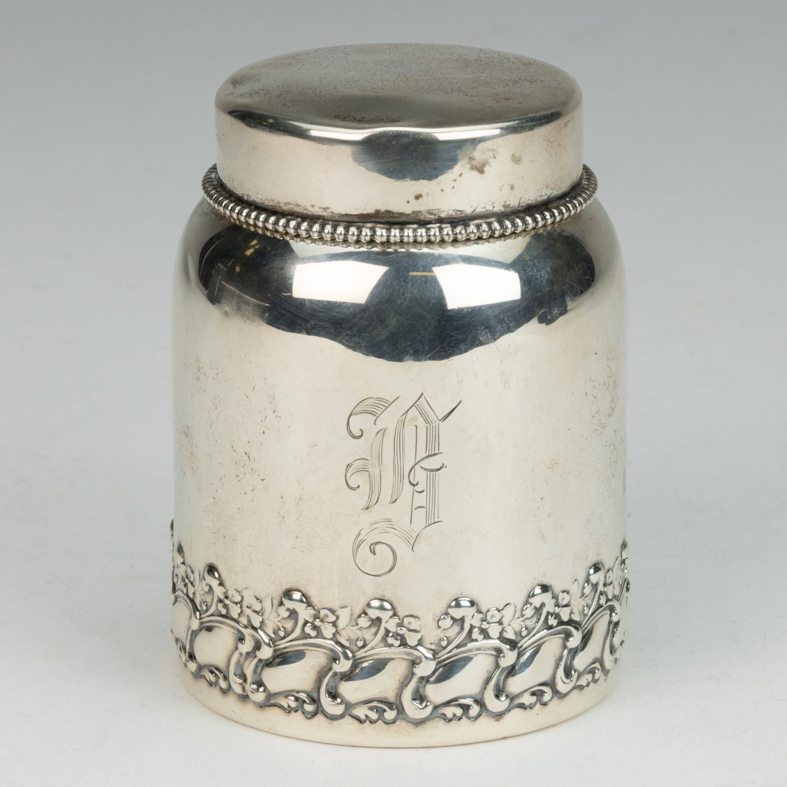 GORHAM STERLING SILVER TEA CADDY: GORHAM STERLING SILVER TEA CADDY, squat cylindrical form with an embossed Art Nouveau floral band around the lower edge, an engraved "B" initial to one side, topped by a round cover with bea
