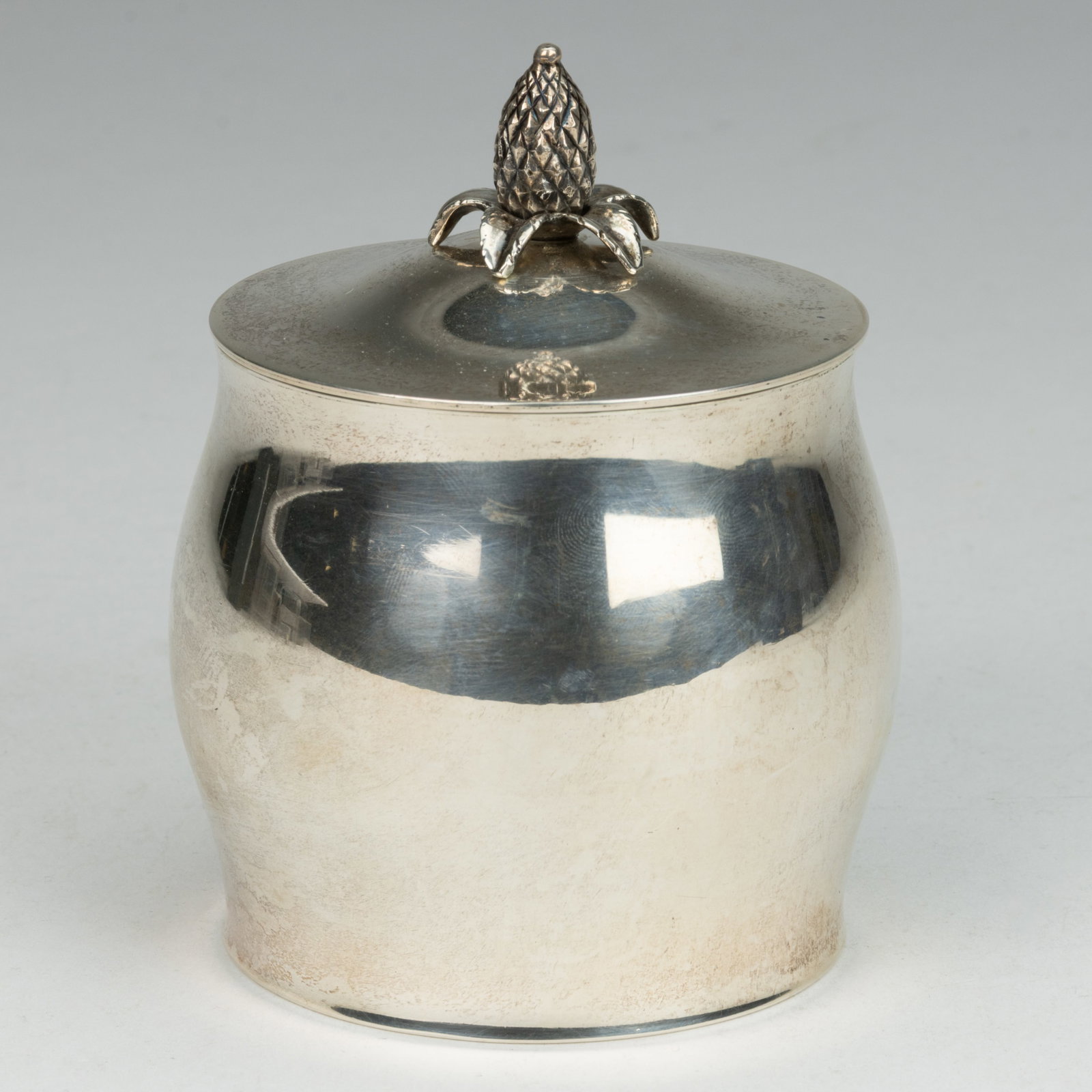 CARTIER RETAILED, TUTTLE PAUL REVERE REPRODUCTION STERLING SILVER TEA CADDY: CARTIER RETAILED, TUTTLE PAUL REVERE REPRODUCTION STERLING SILVER TEA CADDY, plain barrel form, topped by a cover with a figural pineapple finial. Underside impressed with the Tuttle "HH" cr