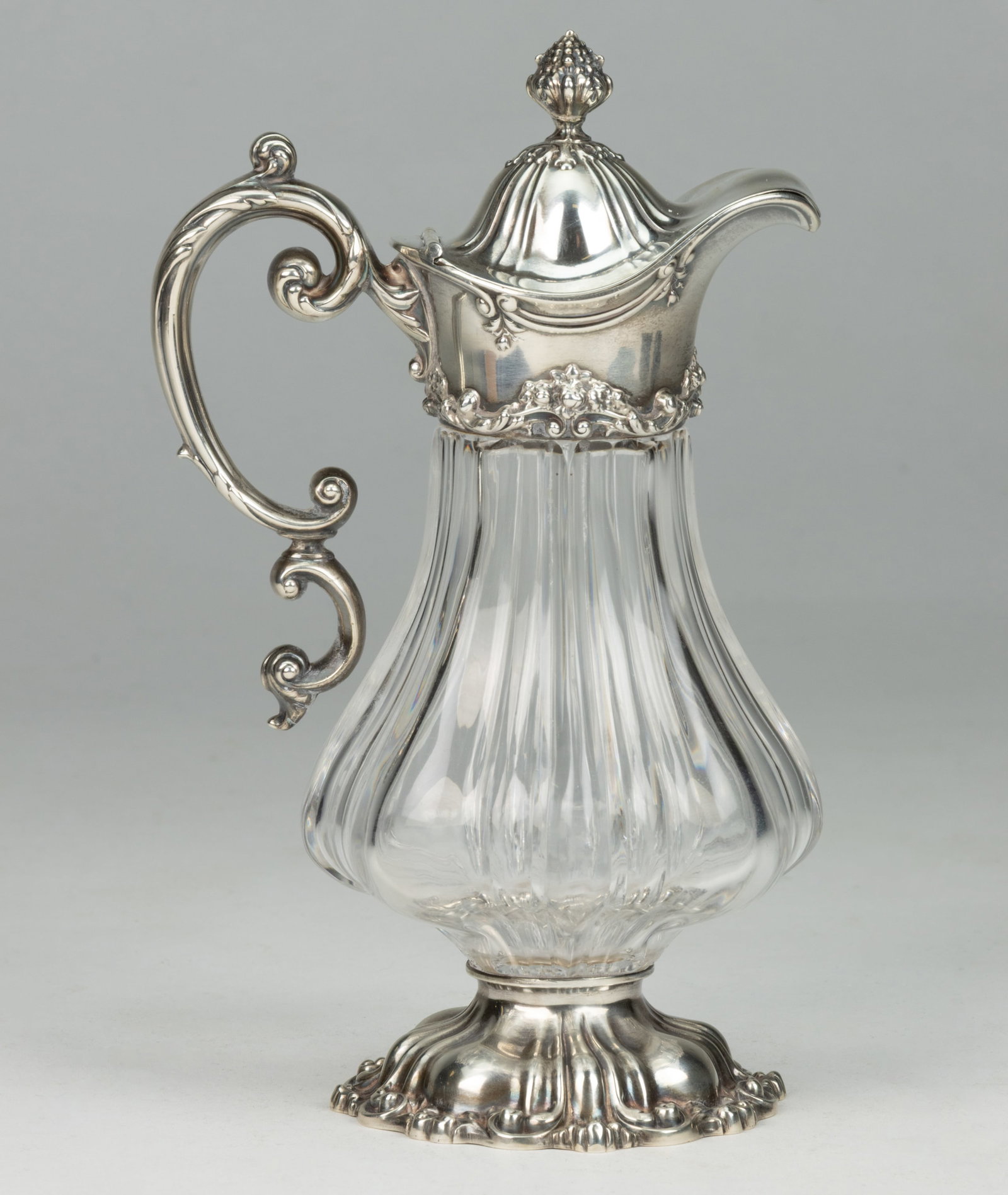 HOWARD & CO., NEW YORK CITY, NEW YORK STERLING SILVER AND CUT-GLASS SYRUP PITCHER: HOWARD & CO., NEW YORK CITY, NEW YORK STERLING SILVER AND CUT-GLASS SYRUP PITCHER, tapered-form colorless glass well with lobes and cut flutes, sterling top having a curved spout, a hinged li