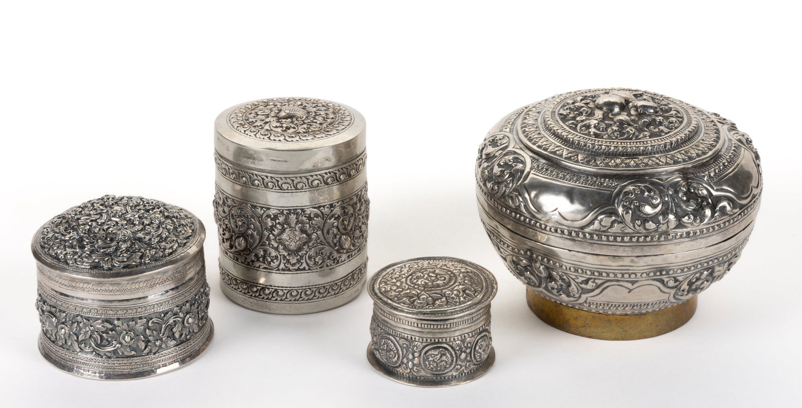 SOUTHEAST ASIAN REPOUSSE SILVER BETEL BOXES, LOT OF FOUR: SOUTHEAST ASIAN REPOUSSE SILVER BETEL BOXES, LOT OF FOUR, each having repousse, chased, and engraved decoration of flowers and other motifs being topped by a cover, including the largest wit