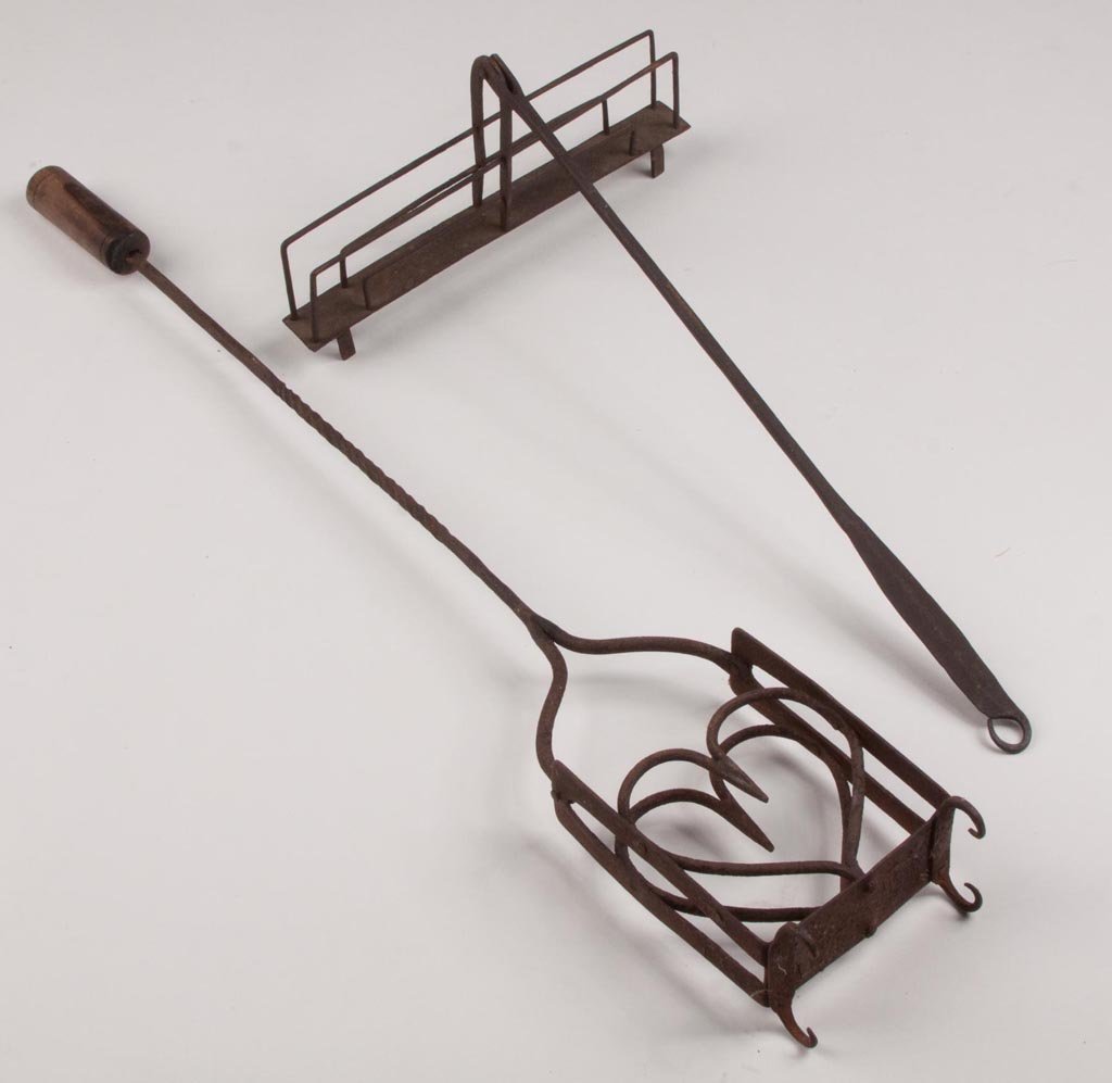 WROUGHT-IRON HEARTH TOASTERS, LOT OF TWO: WROUGHT-IRON HEARTH TOASTERS, LOT OF TWO, comprising an example with heart-form cage and riveted curled feet, spiraling shaft with wooden handle; and other with simple cage construction, straight rive