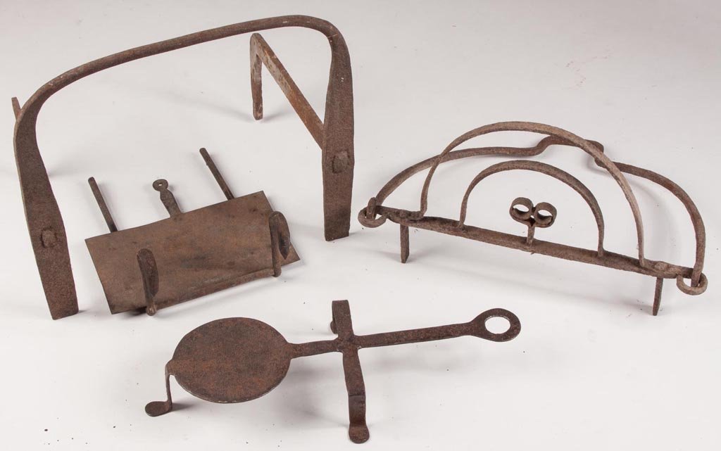 WROUGHT-IRON HEARTH ARTICLES, LOT OF FOUR: WROUGHT-IRON HEARTH ARTICLES, LOT OF FOUR, including a trivet, a sliding warming shelf, and two other articles. 19th century. Various sizes. Provenance: Property of a New England family.