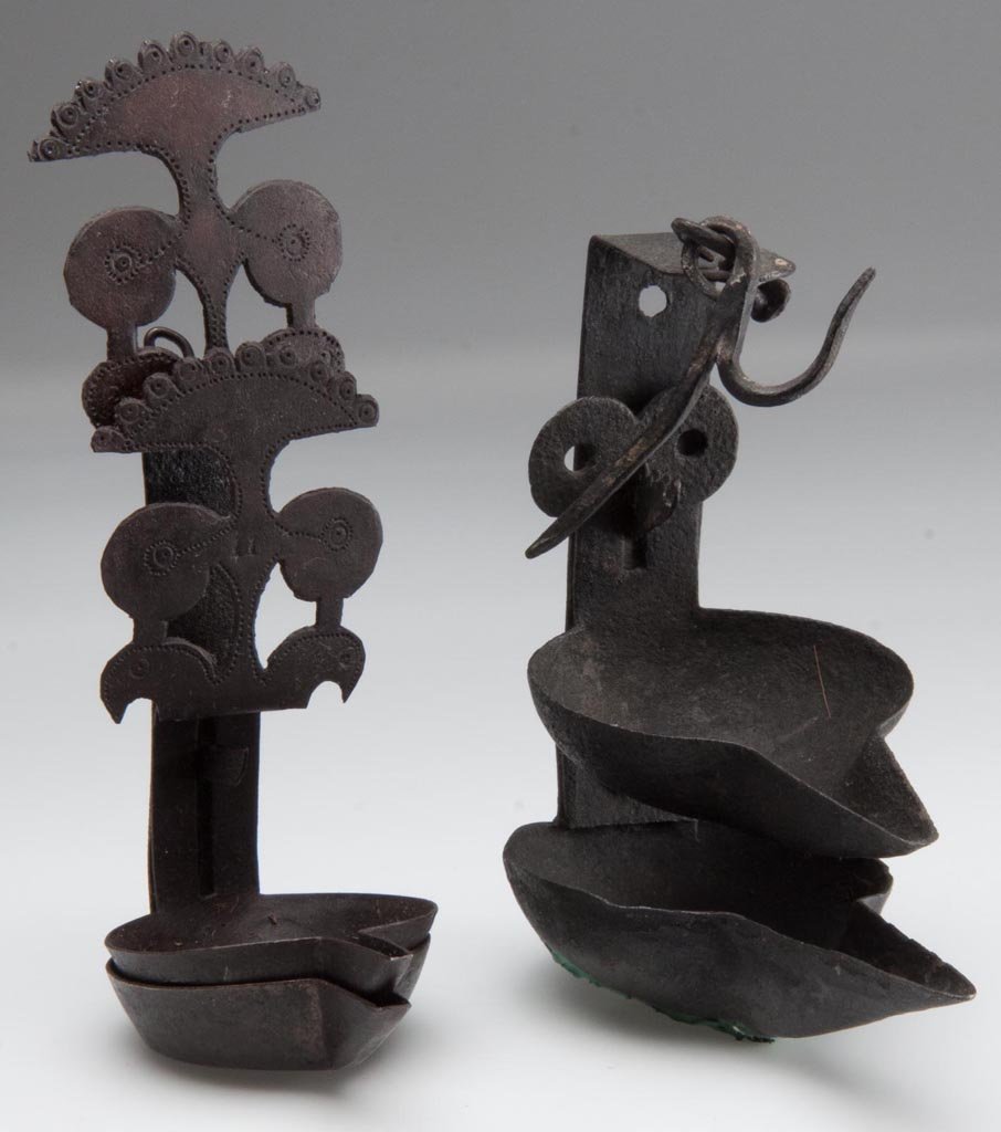 WROUGHT-IRON HANGING DOUBLE CRUSIES , LOT OF TWO: WROUGHT-IRON HANGING DOUBLE CRUSIES , LOT OF TWO, comprising an example with hanger and hook, serrated stud for adjustment of upper reservoir; and remaining example with stylized arches and circles pa